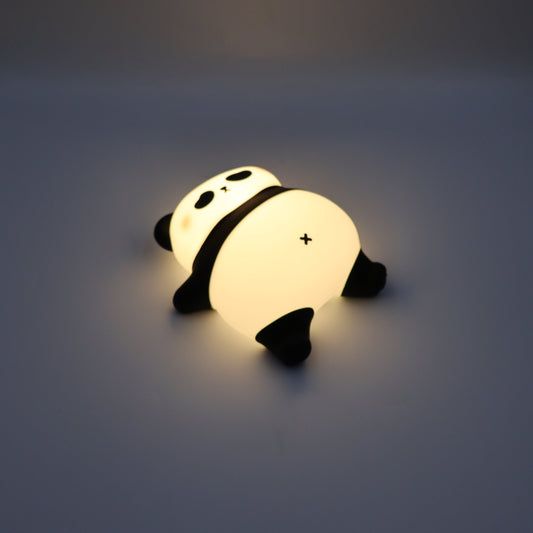 Glowing laying down panda night light on a dark background